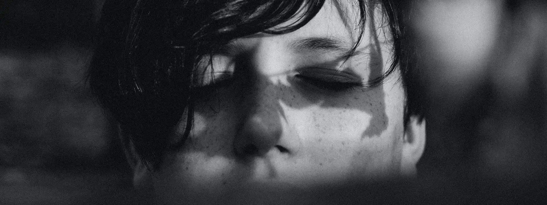 closeup of a young teenage boy's closed eyes in shadow