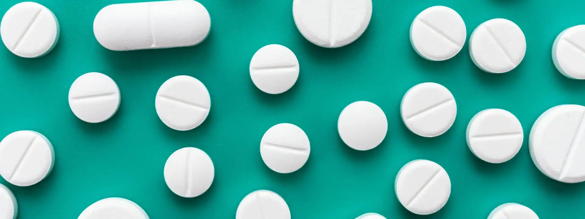 collection of stark white prescription opioids on a bright teal green surface